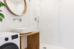 Mirror in white modern bathroom interior with shower and washing machine. Real photo